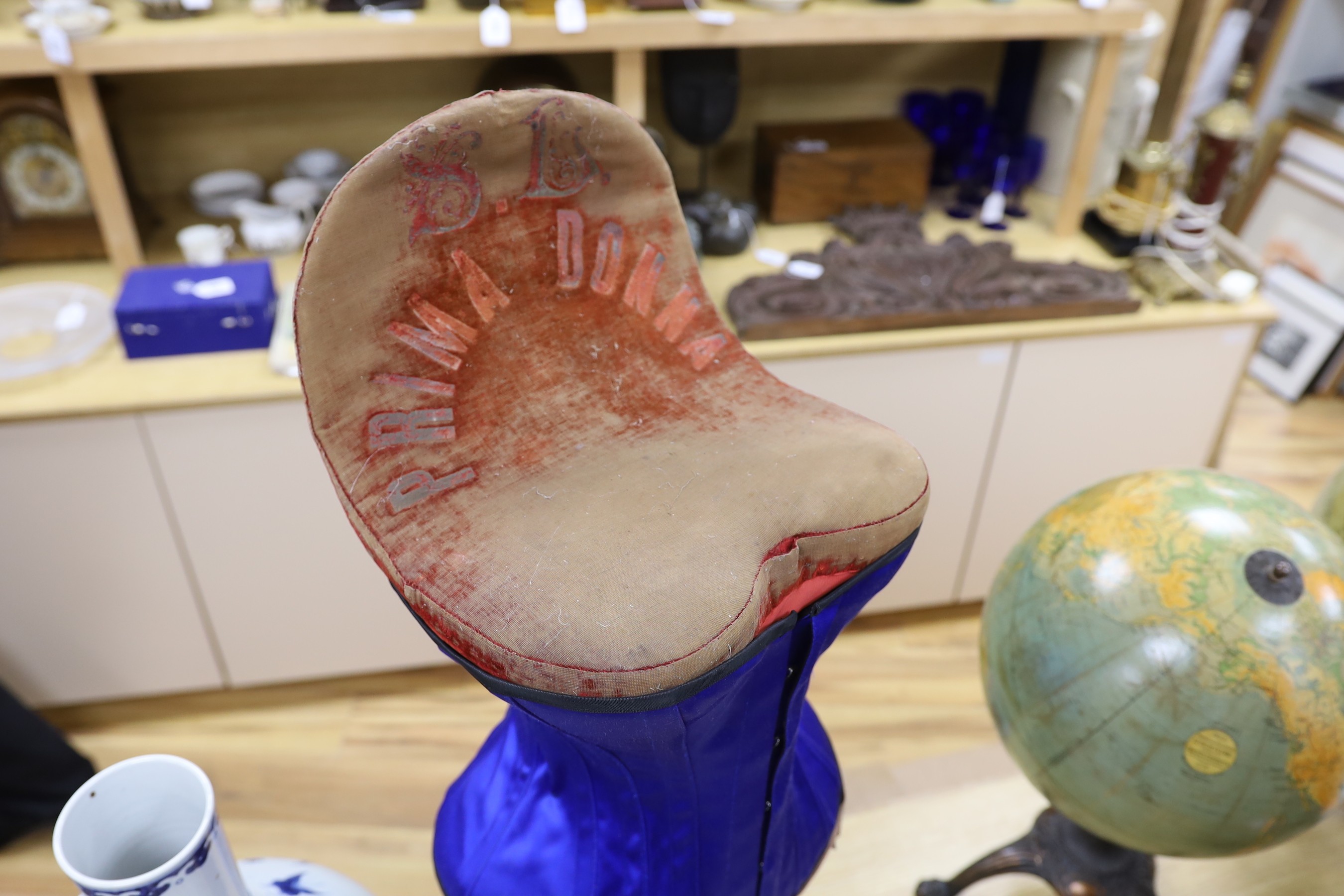 An early 20th century 'Prima Donna' red velvet corset mannequin on turned stand with a contemporary blue satin corset, mannequin, 79cm high
